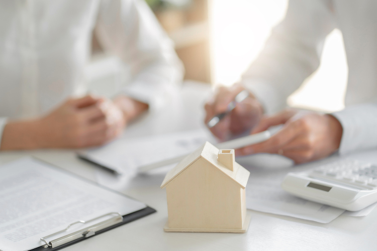 wooden house in front of business people looking over documents